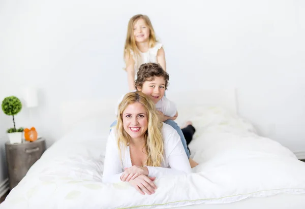 幸せな母と彼女の子供たちはベッドに横たわっての肖像画 — ストック写真