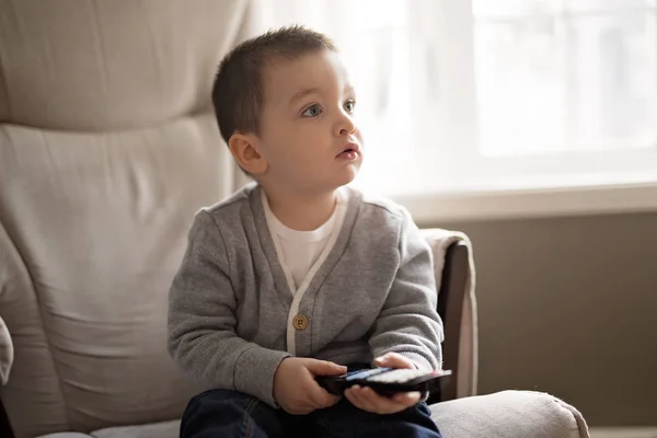 Menino está assistindo tv enquanto sentado em um sofá — Fotografia de Stock