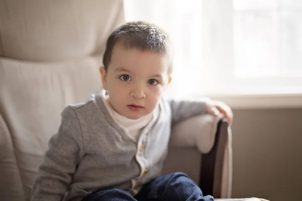 Liten pojke sitter på en soffa — Stockfoto