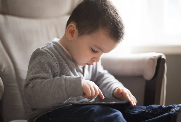 デジタル タブレットを使用して小さな男の子がリビング ルームに座ってください。 — ストック写真