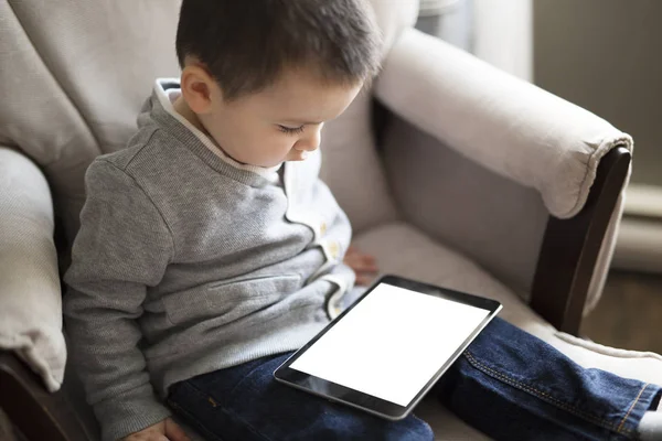 デジタル タブレットを使用して小さな男の子がリビング ルームに座ってください。 — ストック写真