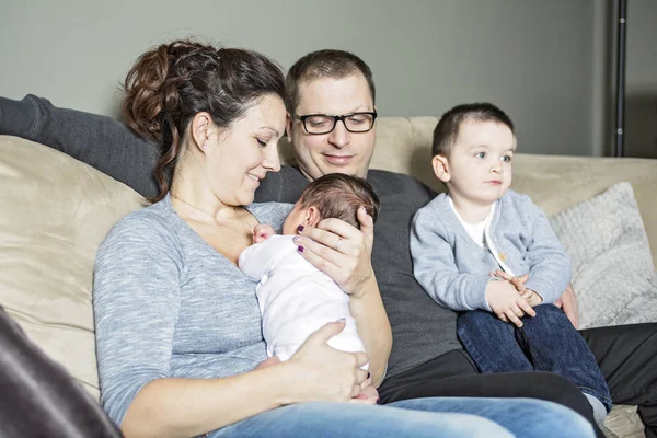Jovem família feliz com duas crianças em casa — Fotografia de Stock