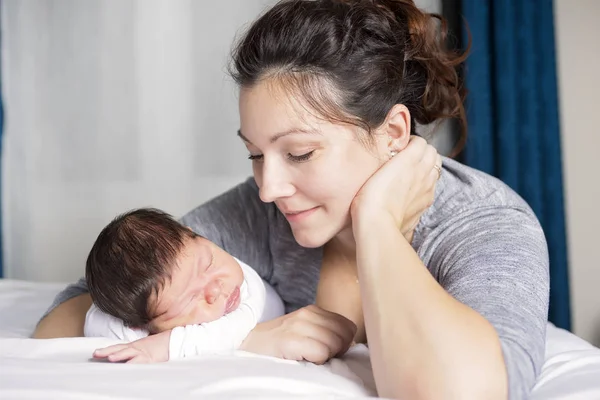 Mãe feliz e bebê deitado na cama em casa — Fotografia de Stock