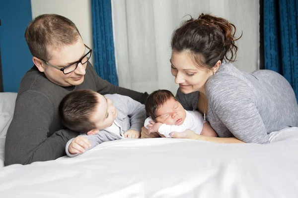 Feliz familia madre, padre y dos hijos en casa en la cama — Foto de Stock
