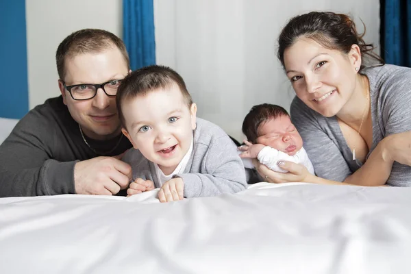 Gelukkige familie moeder, vader en twee kinderen thuis in bed — Stockfoto