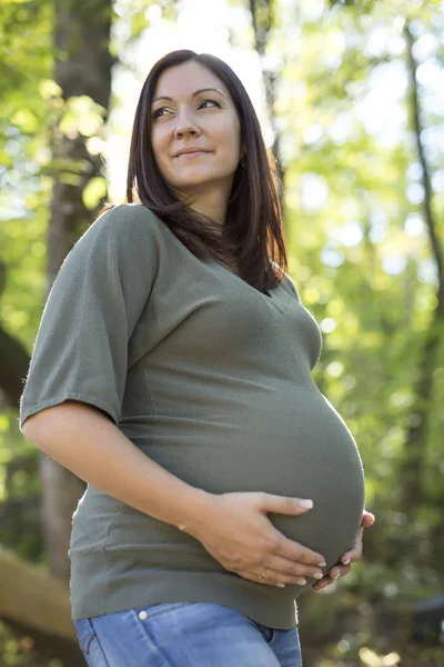 Krásná těhotná žena uvolňující na park — Stock fotografie