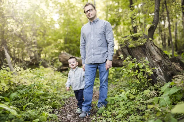 Malý chlapec a jeho otec na trávě v podzimním lese — Stock fotografie