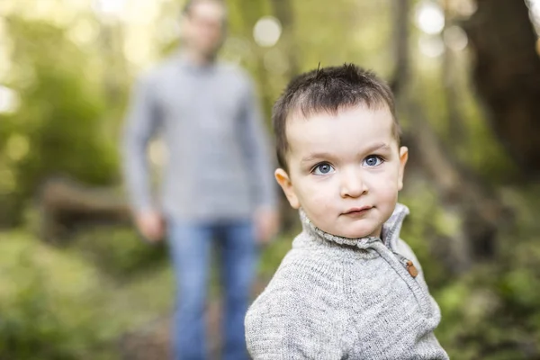 Маленький хлопчик і його батько на траві в осінньому лісі — стокове фото