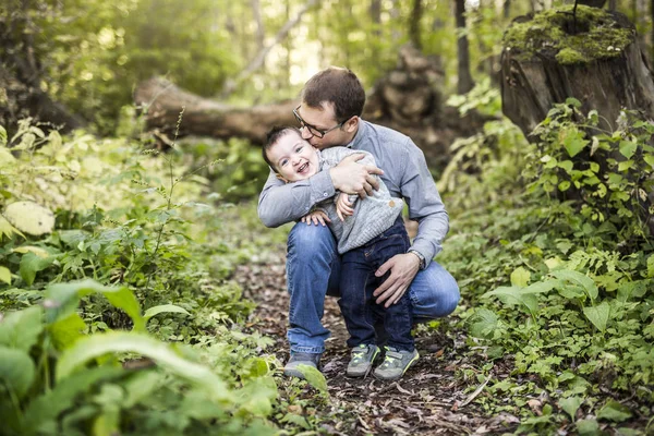 Petit garçon et son père sur l'herbe dans la forêt d'automne — Photo