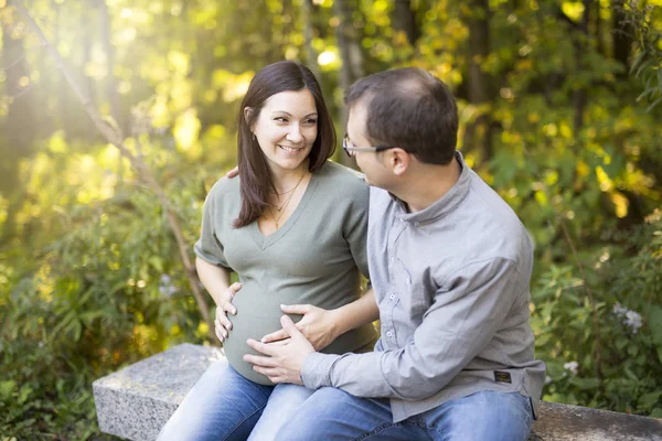 Beautiful pregnant couple relaxing outside in the park. — Stock Photo, Image