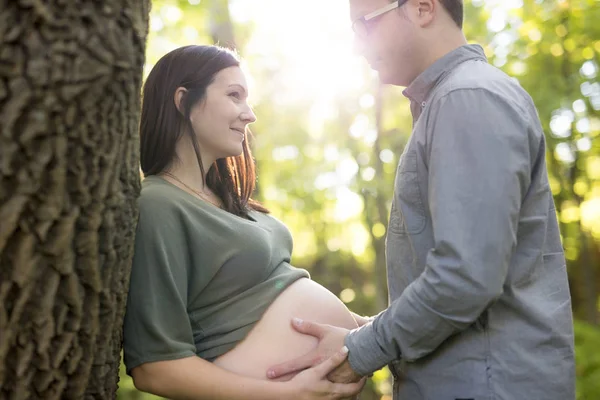 Casal grávida bonita relaxante lá fora no parque . — Fotografia de Stock