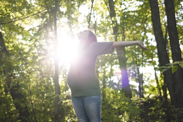 Krásná těhotná žena uvolňující na park — Stock fotografie