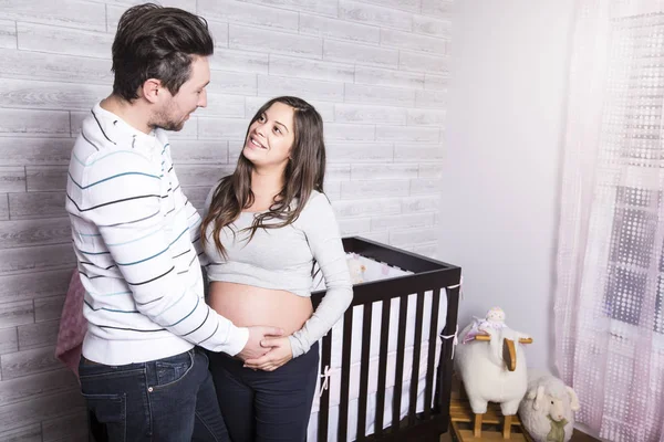 Mãe grávida e seu marido no quarto de bebê — Fotografia de Stock