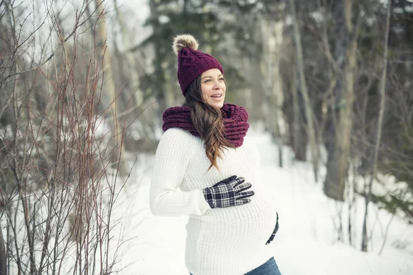 Young happy pregnant woman in snowy forest — Stock Photo, Image