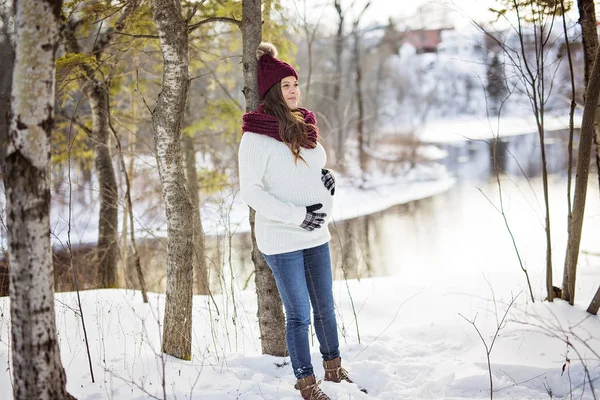 Young happy pregnant woman in snowy forest — Stock Photo, Image
