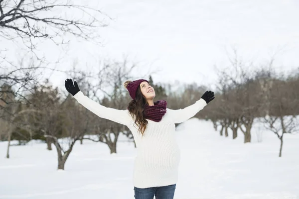 Young happy pregnant woman in snowy forest — Stock Photo, Image