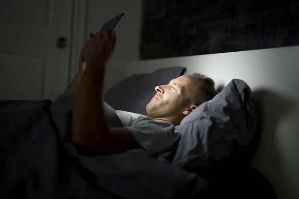 Hombre trabajando de noche, acostado en la cama —  Fotos de Stock