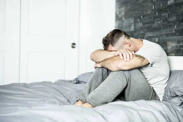 Ill man sitting on his bed — Stock Photo, Image