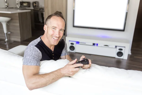 Man on sofa linstening TV — Stock Photo, Image