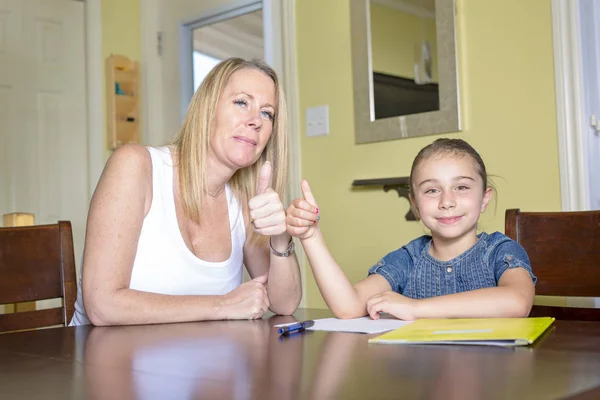 Madre e figlia a casa. Mamma insegna a fare i compiti a casa a bambina . — Foto Stock