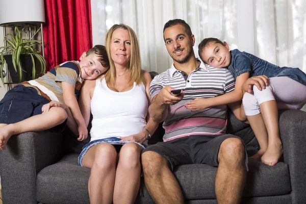 Familie van vier op de sofa in de woonkamer — Stockfoto