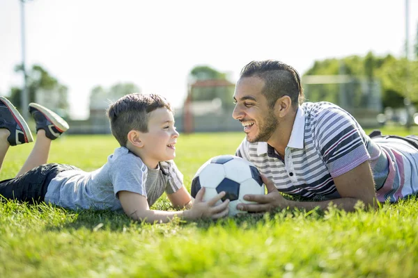 Man met kind voetballen op het veld — Stockfoto