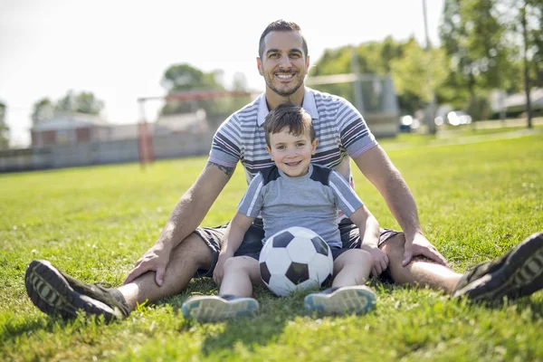 Man med barn som spelar fotboll på fältet — Stockfoto