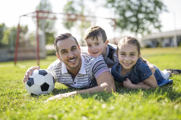 Man med barn som spelar fotboll på fältet — Stockfoto