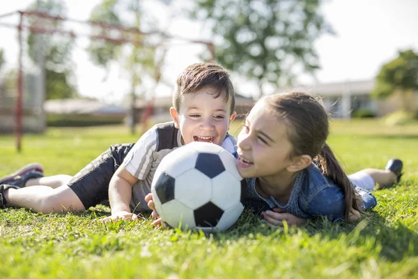 Criança jogando futebol no campo com a irmã — Fotografia de Stock