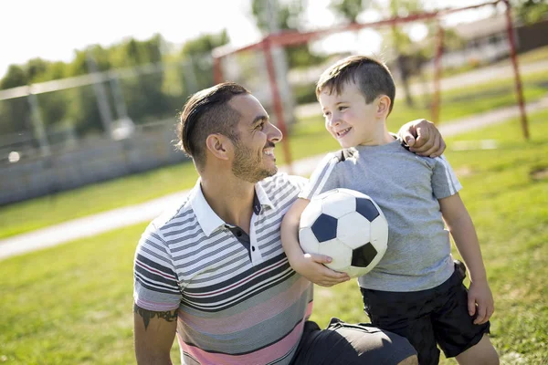 Man med barn som spelar fotboll på fältet — Stockfoto