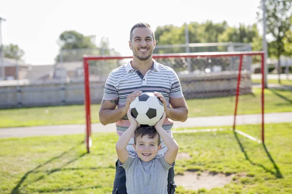 Man met kind voetballen op het veld — Stockfoto