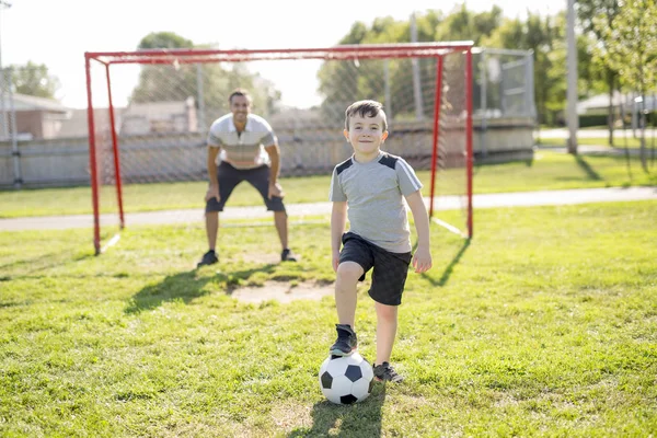 Hombre con niño jugando al fútbol en el campo —  Fotos de Stock