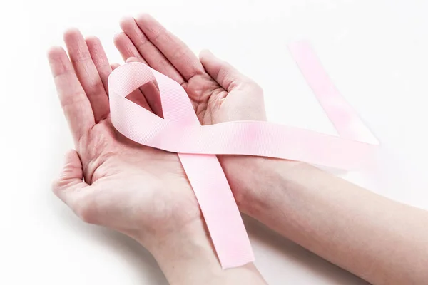 Närbild gammal kvinna hand med rosa bandet på vit bakgrund, medvetenhet bröstcancer cancer koncept — Stockfoto