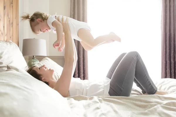 赤ちゃんのベッドの上で若い母 — ストック写真