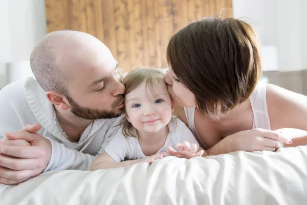 子供連れのご家族。幸せな親のベッドに赤ちゃんと遊ぶ — ストック写真