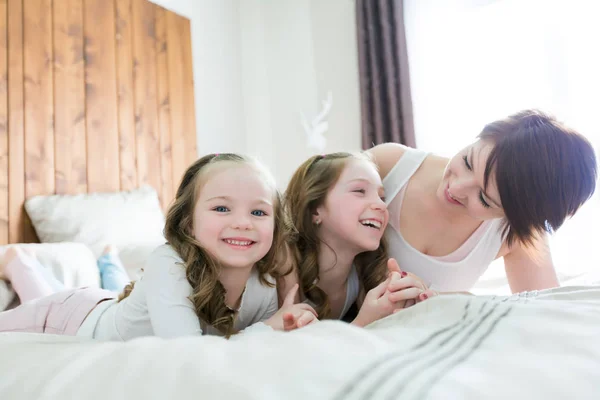 Moeder en twee kinderen in de slaapkamer op bed — Stockfoto