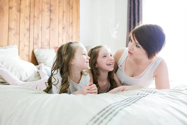 Moeder en twee kinderen in de slaapkamer op bed — Stockfoto