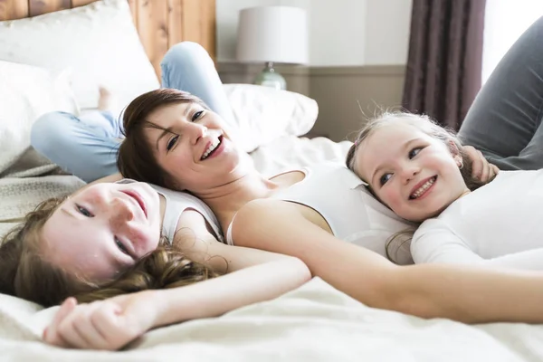Мать и двое детей в спальне на кровати — стоковое фото