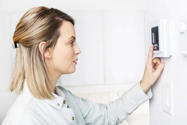 Frau stellte Thermostat am Haus auf. — Stockfoto