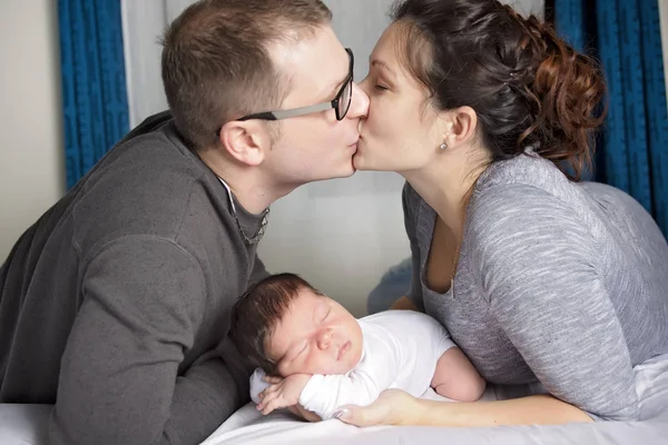 Família feliz com bebê recém-nascido na cama no quarto — Fotografia de Stock