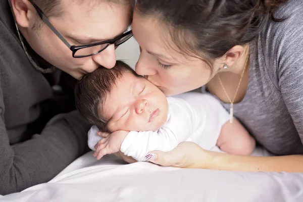 Família feliz com bebê recém-nascido na cama no quarto — Fotografia de Stock