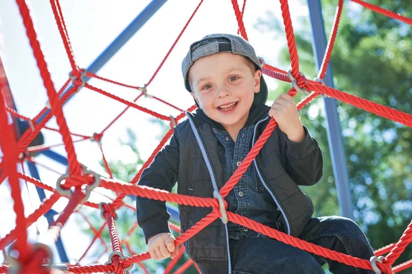 Joyeux petit garçon grimpé sur l'aire de jeux — Photo