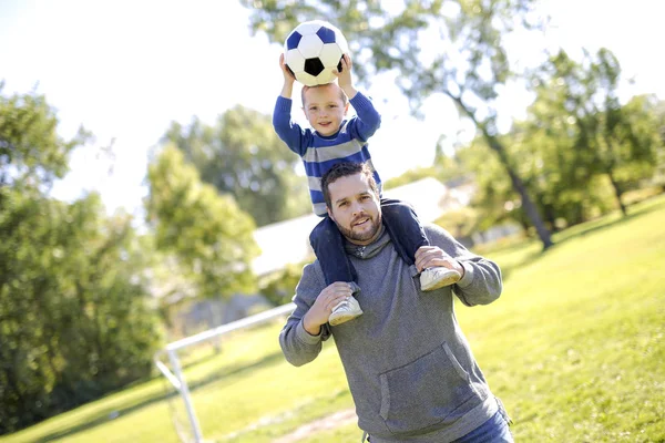 Far och son spelar boll i parken — Stockfoto