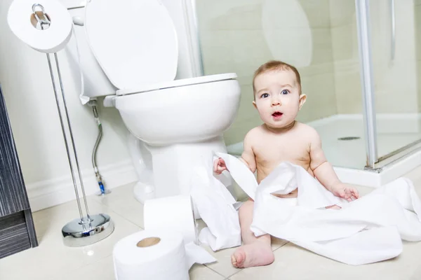 Peuter scheurt wc-papier in de badkamer — Stockfoto