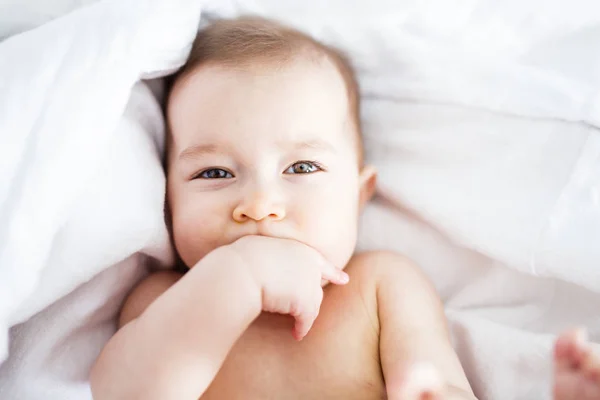 Bambina sdraiata su lenzuolo bianco — Foto Stock