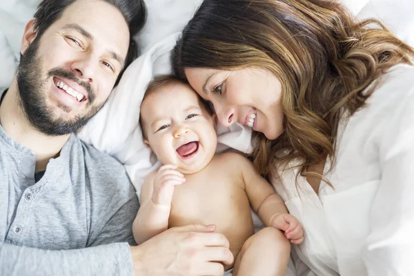 Madre padre e hijo bebé en una cama blanca. — Foto de Stock