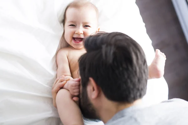 Feliz padre jugando con adorable bebé en el dormitorio — Foto de Stock