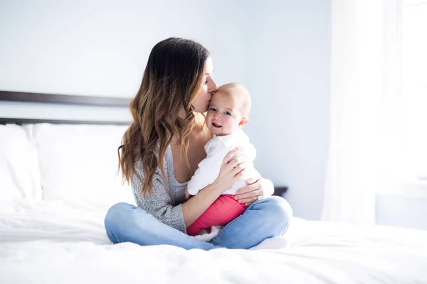 Mãe e bebê criança em uma cama branca . — Fotografia de Stock