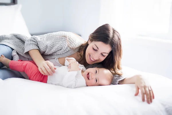 Mère et bébé enfant sur un lit blanc . — Photo