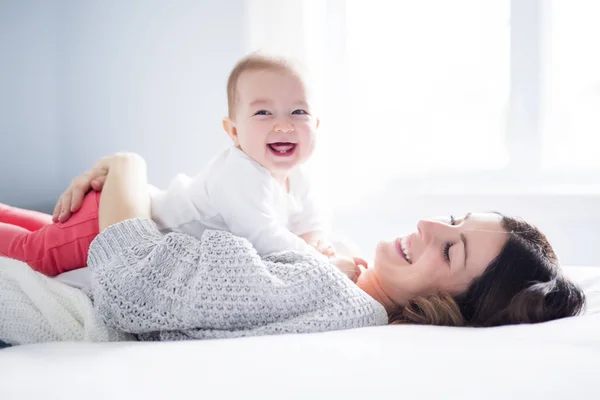 Mãe e bebê criança em uma cama branca . — Fotografia de Stock